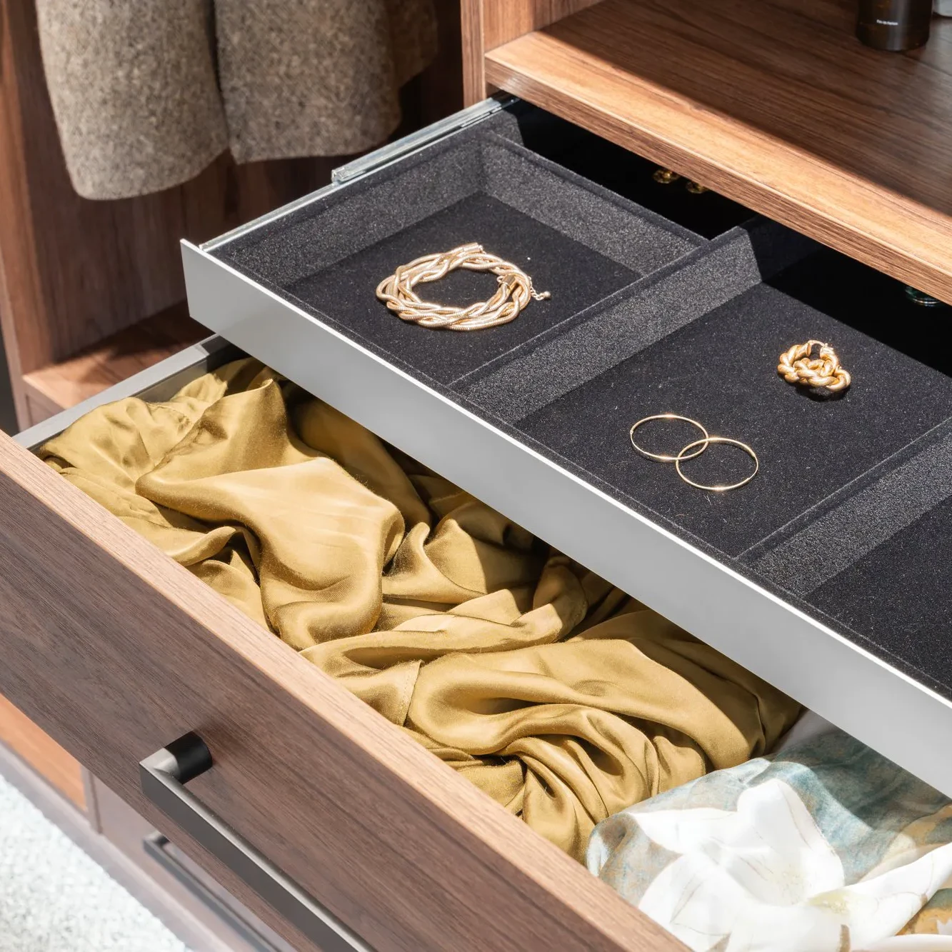 Jewellery drawer in a wardrobe is open showing earrings and bracelents