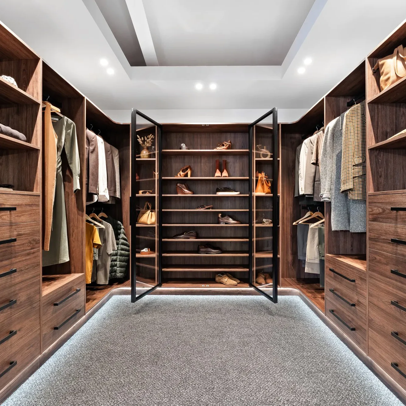 A Luxe walk-in wardrobe in dark woodgrain finish with glass doors